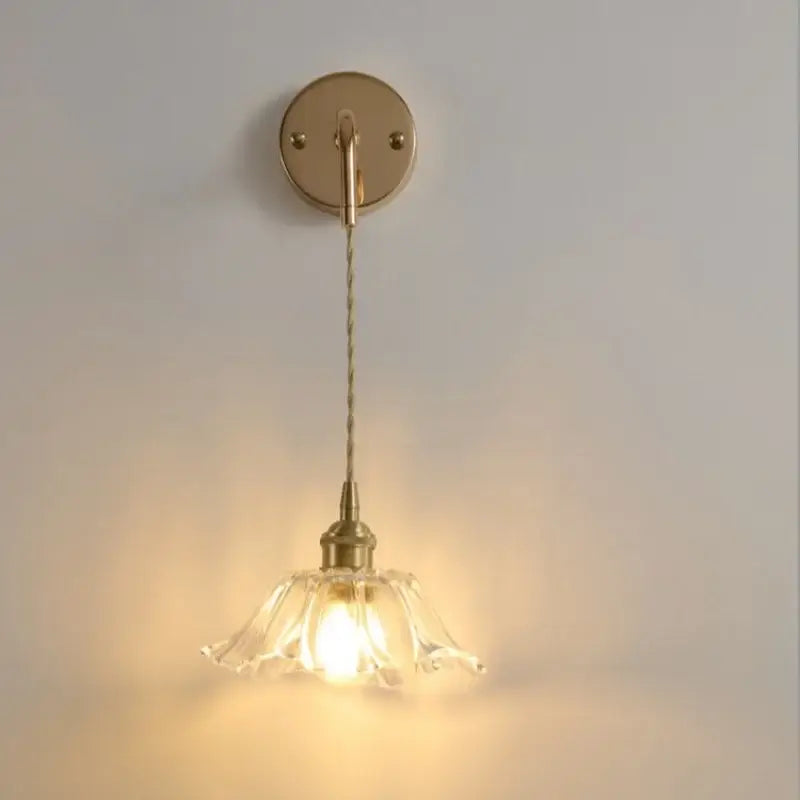 A delicate brass wall light with a clear glass led petal-shaped shade for modern bedroom decorbites clear glass lighting
