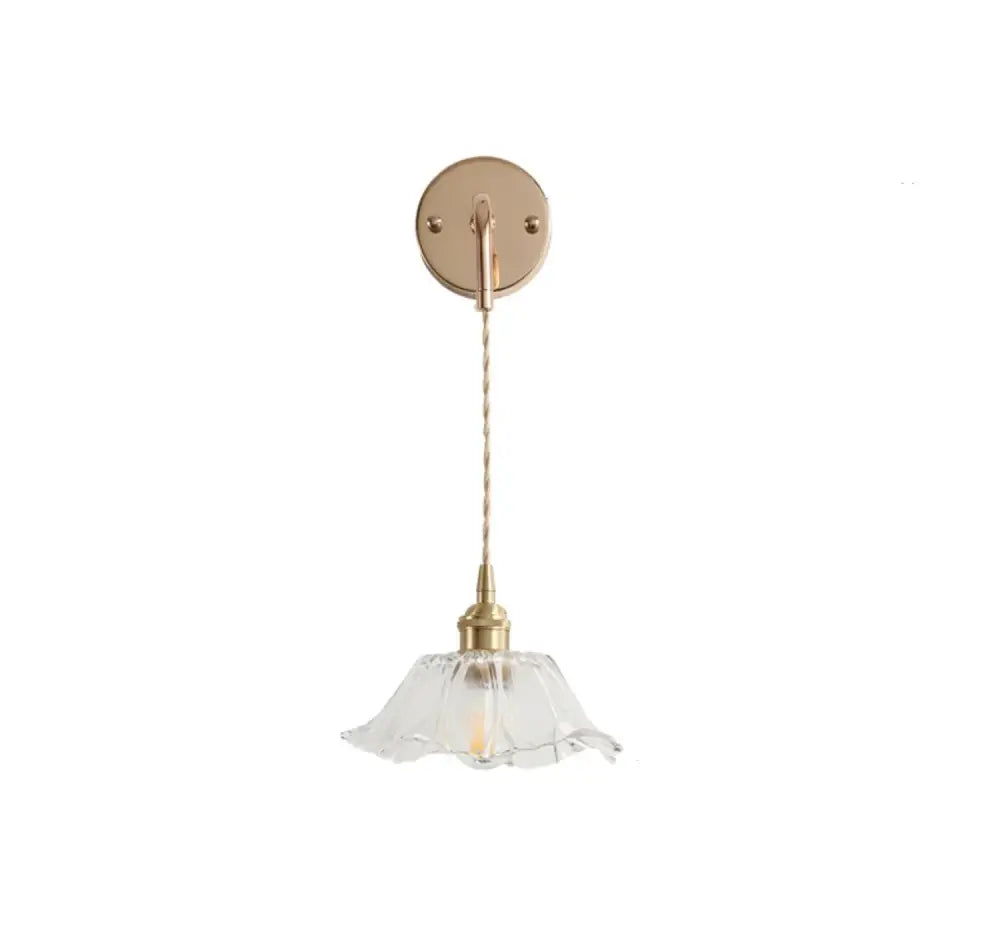 A modern brass-finished wall light with decorbites clear glass petal-shaped shade and clear glass led bulb
