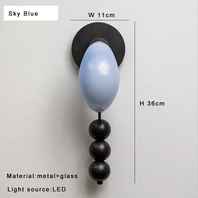 Modern wall lamp featuring sky blue glass orb with black metal base and spherical accents for decorbites brass curve glass decor