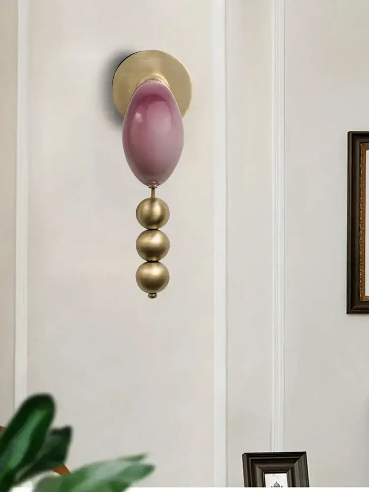 Modern pink and brass curve glass wall lamp features a translucent lavender globe above polished brass spheres decorbites brass curve