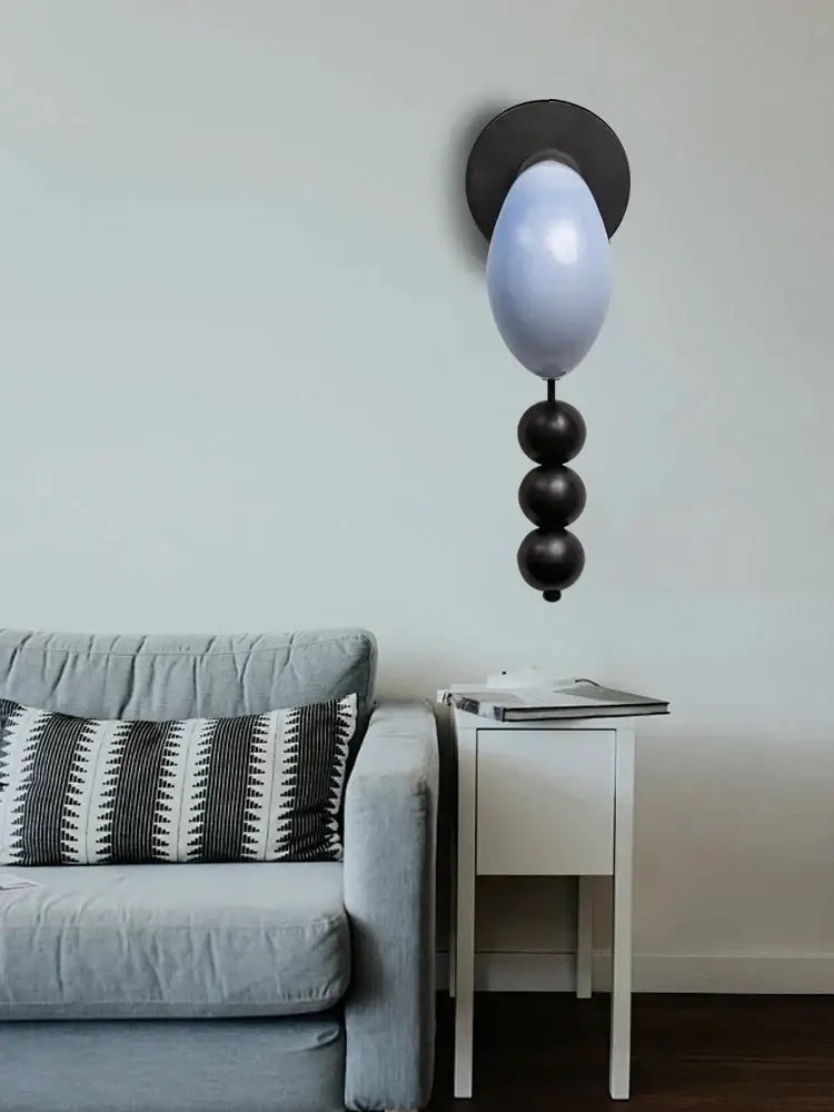 Modern wall lamp with matte black base, frosted glass bulb, and decorbites brass curve glass glossy black beads design