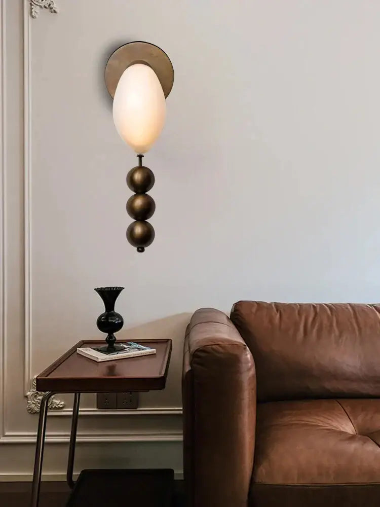 Modern pink and brass curve glass wall lamp with ivory frosted shade and three stacked bronze spheres decorbites brass curve