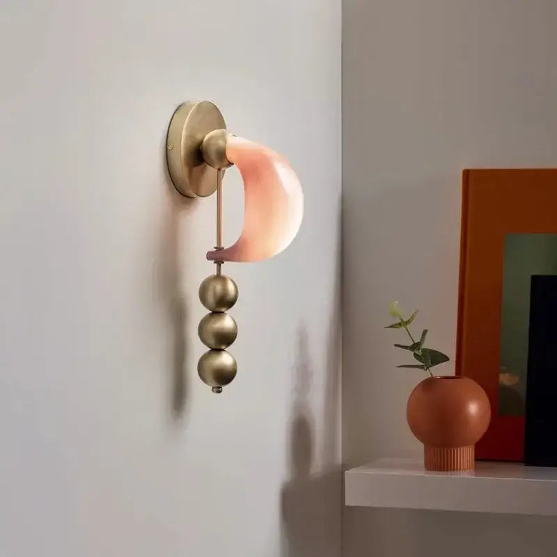 Modern pink and brass curve glass wall lamp featuring a soft pink curved shade and polished brass spheres for bedroom decorbites brass curve
