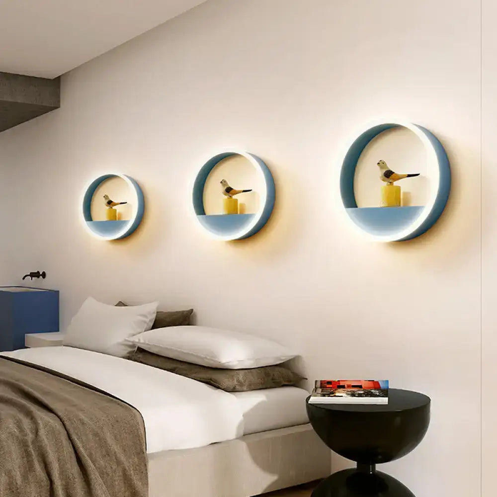 Modern pink and blue iron hoop wall light with blue rim LED rings and bird figurines on yellow bedroom storage rack