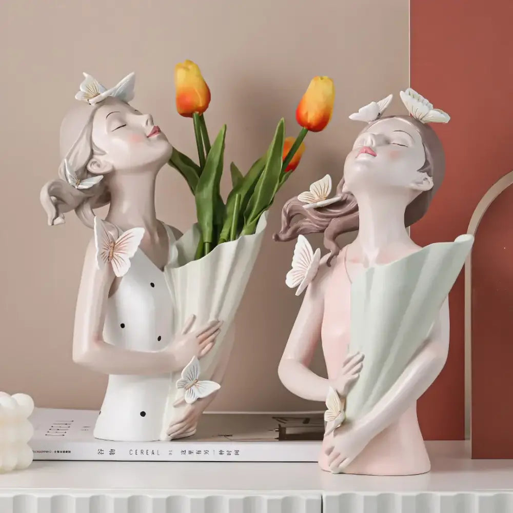 Two modern pink resin butterfly girl sculptures holding tulips with butterflies on hair and shoulders for living room decor