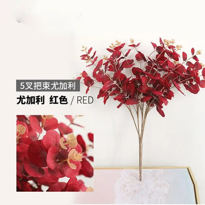 Modern pink eucalyptus flower arrangement featuring red artificial eucalyptus flowers with glossy leaves in a glass vase