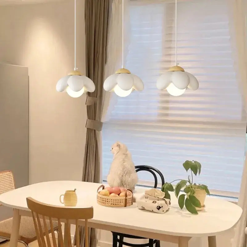 Three white cream flower pendant lights with wooden accents hang above a dining table for modern decorbites decor