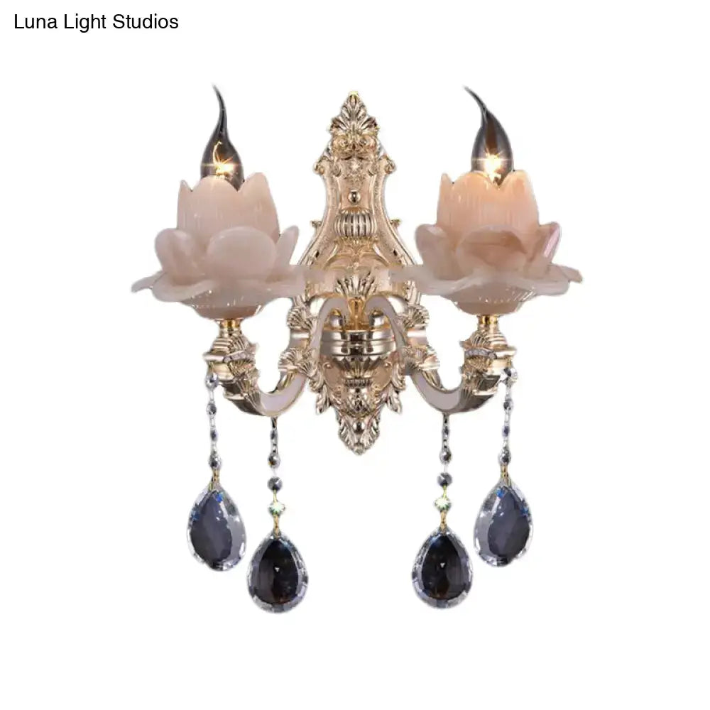Gold-toned modern pink lotus wall lamp with milky glass shades and dangling dark blue teardrop crystal bedroom sconce