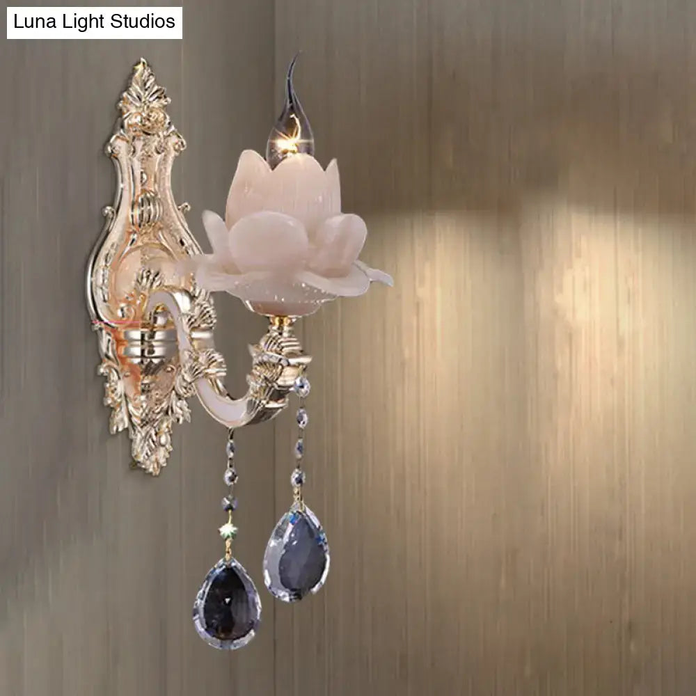 Elegant gold-toned wall lamp with milky pink lotus glass shade and dangling teardrop crystal for bedroom sconce