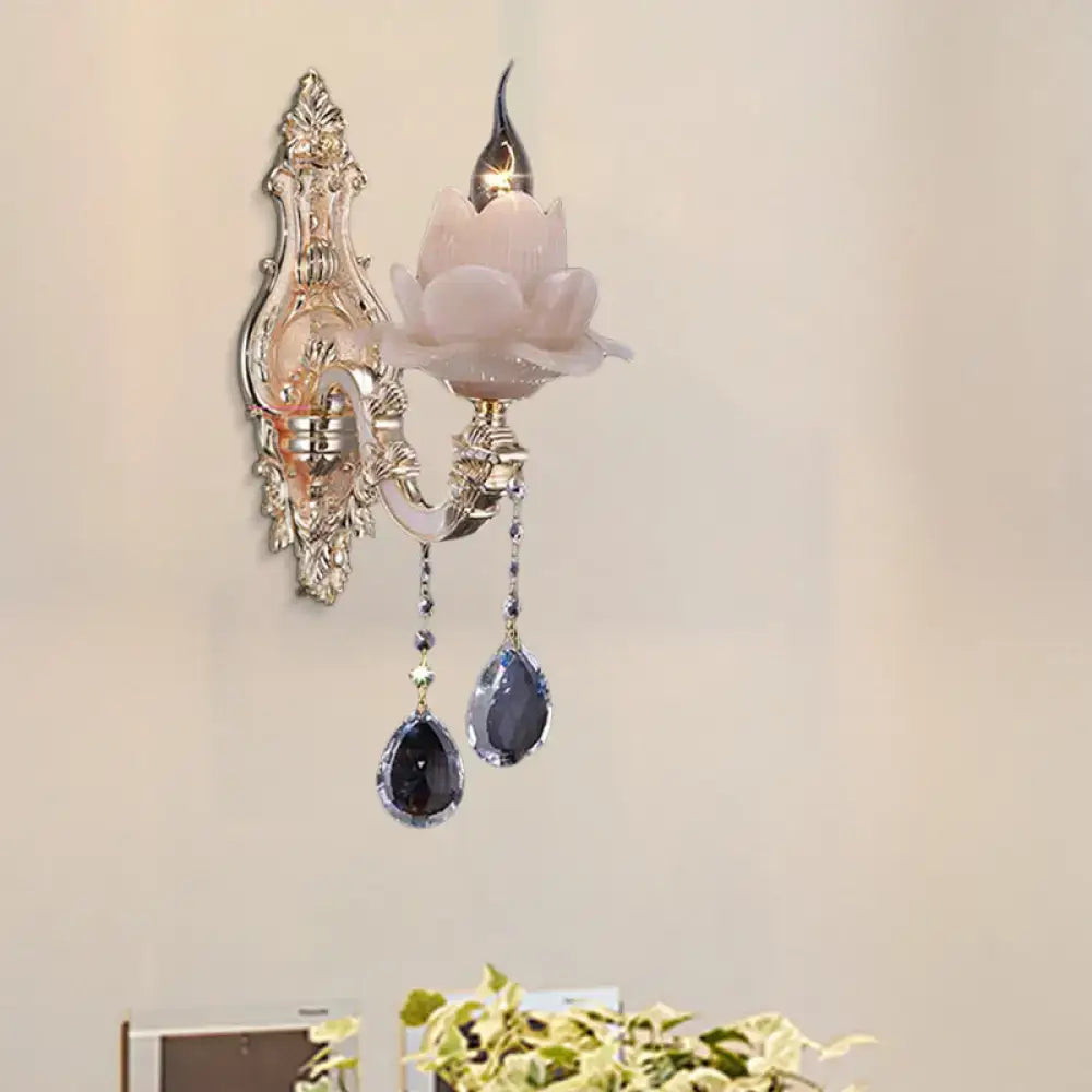 Elegant silver-toned wall lamp with pink milky glass lotus shade and dark teardrop crystal accents for bedroom sconce