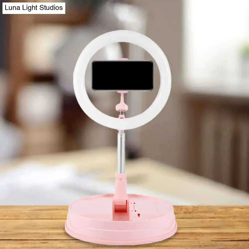 Modern pink metallic led ring flash light with white and pink light and smartphone on adjustable bedroom stand