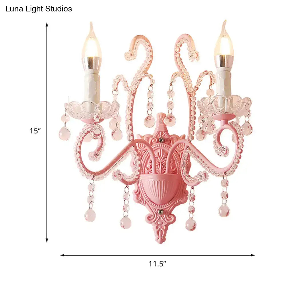 Modern pink metallic scroll arm wall lamp with crystal droplets and two candle-shaped bulbs for bedroom sconce lighting