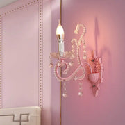 Modern pink metallic scroll arm wall lamp with crystal accents and candle-style bulb for bedroom sconce lighting