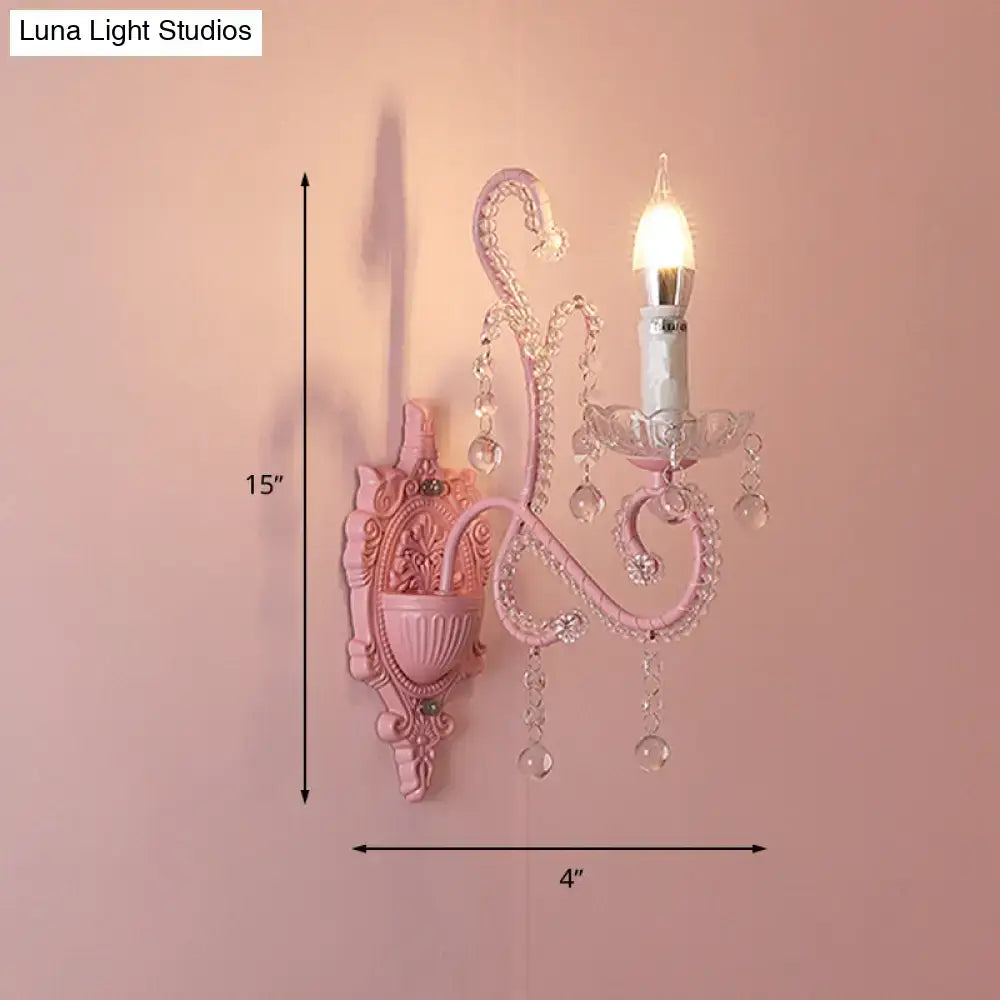Modern pink metallic scroll arm wall lamp with ornate crystal droplets and candle-style bulb for bedroom sconce lighting