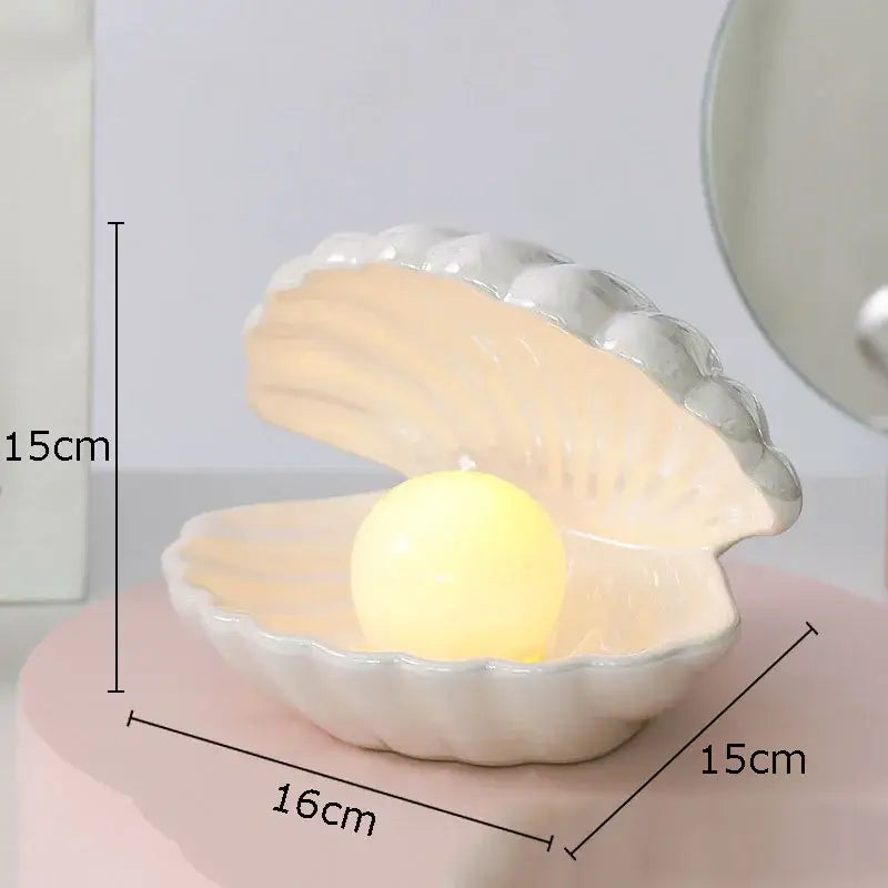 A delicate white ceramic shell lamp desk decoration with a glowing yellow orb for modern bedroom use