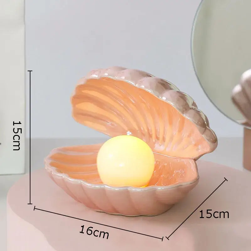 Modern pink and off-white pearl shell lamp desk decoration featuring a pastel pink ceramic clamshell with glowing yellow light