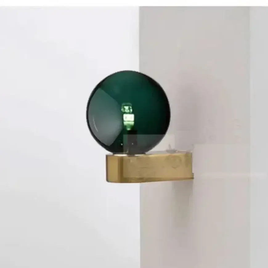 A sleek dark green glass ball led wall lamp with a polished brass base from decorbites glass ball collection