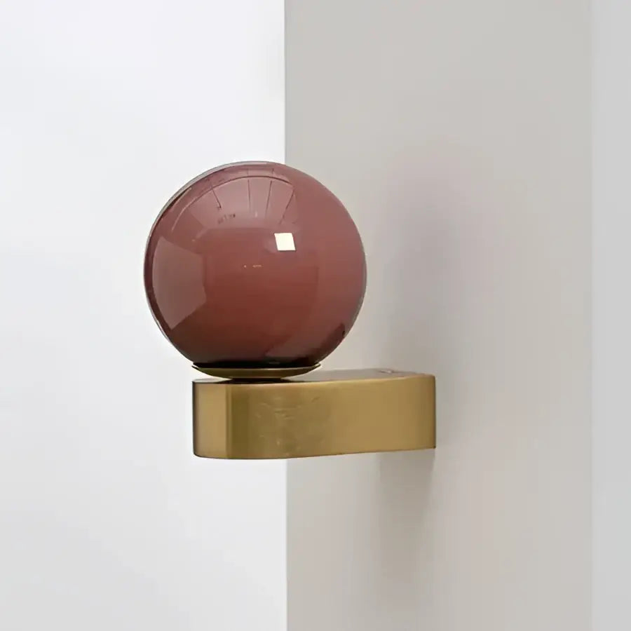 A sleek matte rose-gold spherical knob on a brass base for modern pink and orange decorbites glass ball led wall lamp
