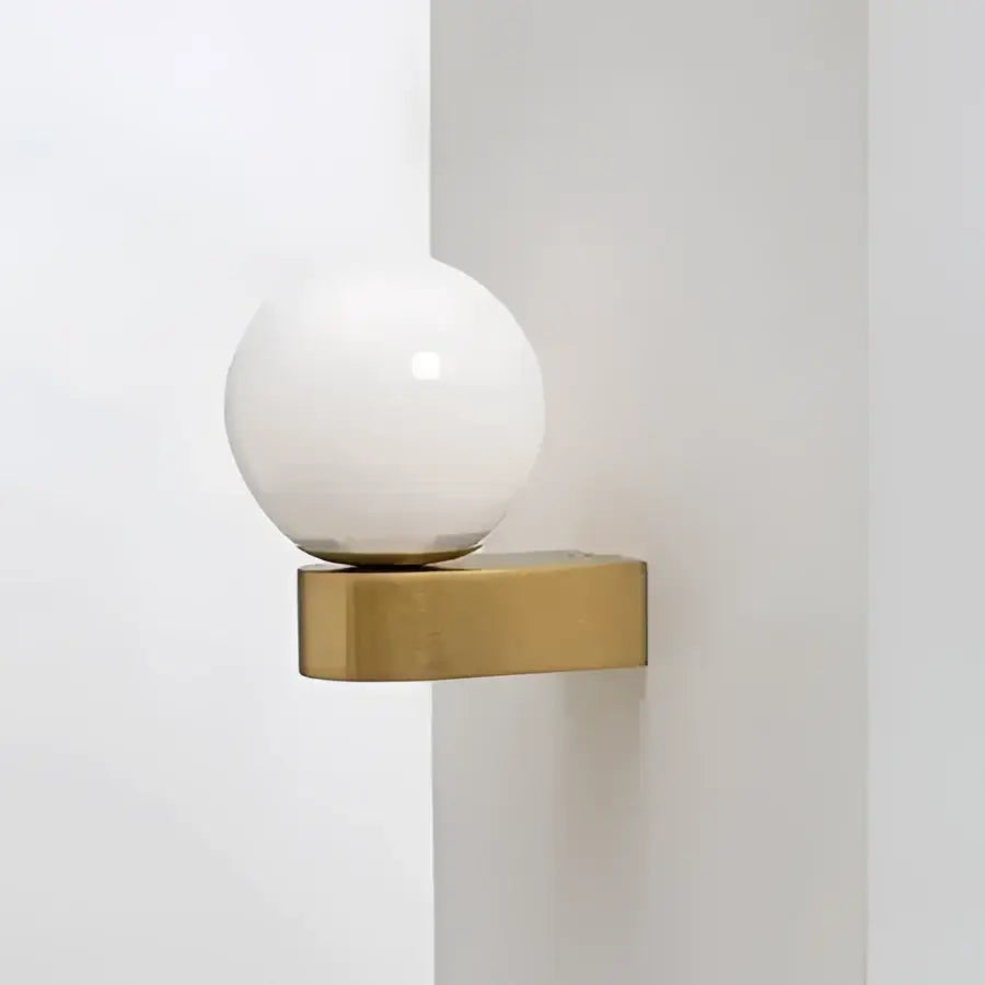 A sleek spherical white glass ball led wall lamp on a minimalist gold-toned decorbites glass ball bracket