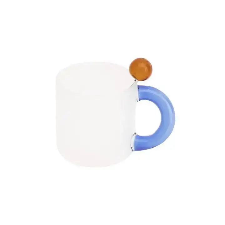 A modern glass mug set includes a frosted white glass mug with a vibrant blue handle and amber accent