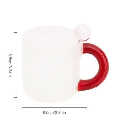 A frosted white ceramic mug with a glossy red handle and clear glass sphere from a modern pink and red glass mug set