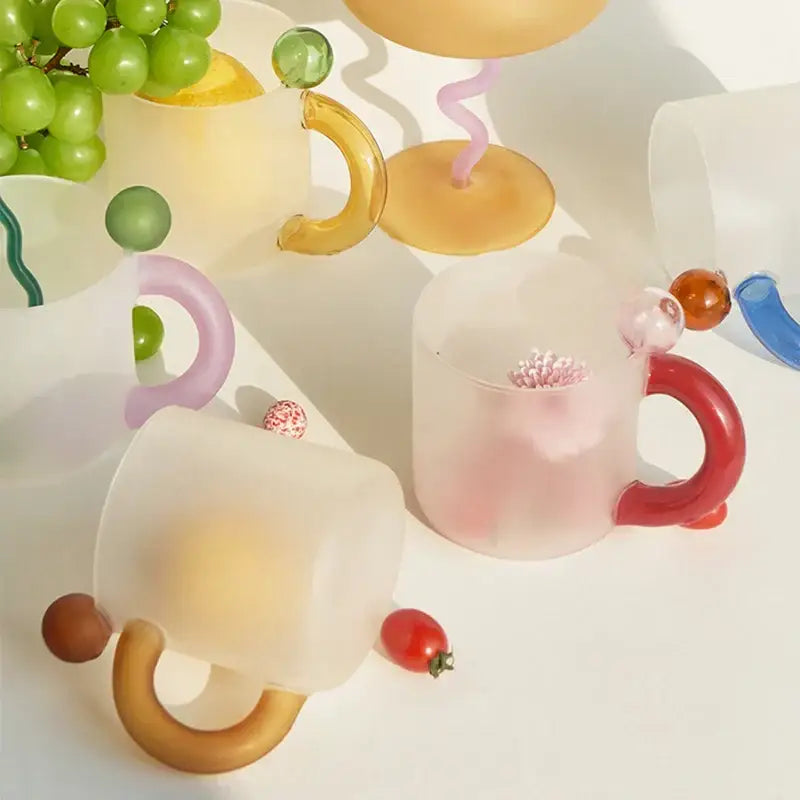 A translucent frosted glass mug with a vibrant red handle from a modern pink and red glass mug set