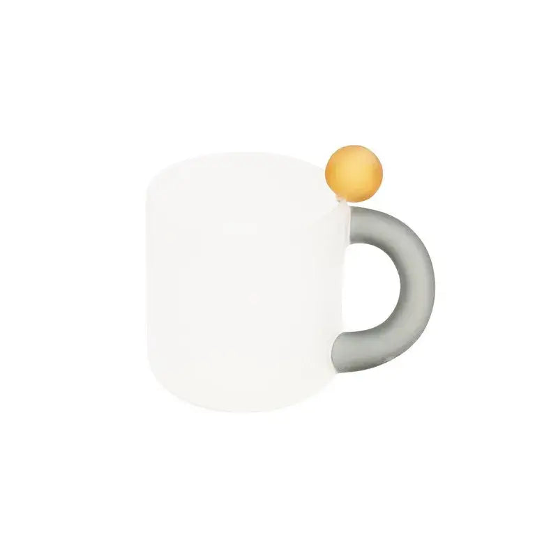 White ceramic mug with gray handle and golden sphere detail from modern pink and red glass mug set for dining room use