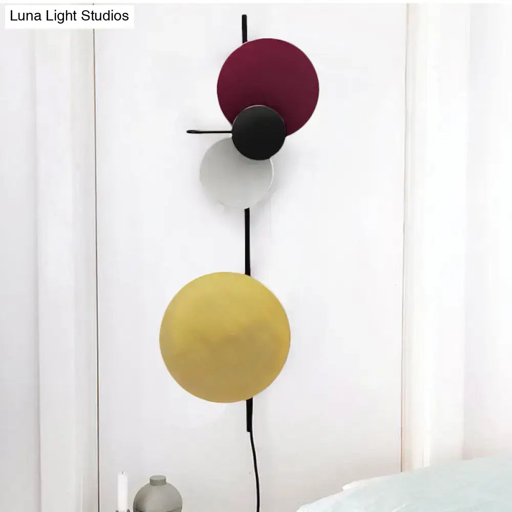 Modern circular wall mount light with stacked burgundy black white and mustard yellow shades for living room use
