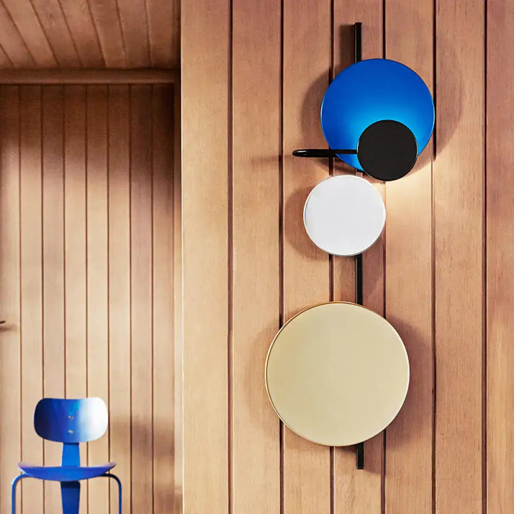 Modern circular wall mount light for living room with three stacked blue, white, and cream shades on black metal arms