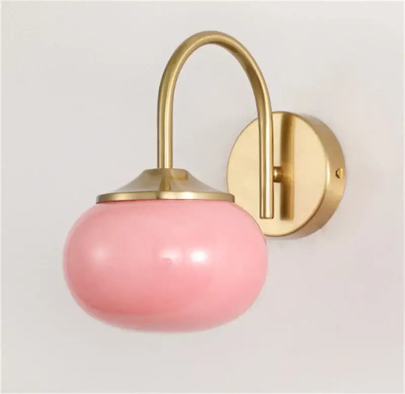 Modern pink and white glass ball wall lamp with soft pink glass and brass-finished metal arm by decorbites
