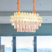 A modern dining room pendant chandelier with clear crystal pinkish-gold prisms and yellow oval glass discs