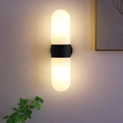 Modern minimalist vanity mirror light with frosted glass cylinder and black metal band for bathroom sconce illumination