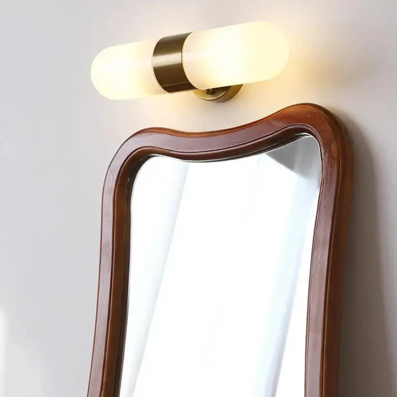 Warm-toned cylindrical vanity mirror light with frosted glass and brass accents for modern bathroom sconces