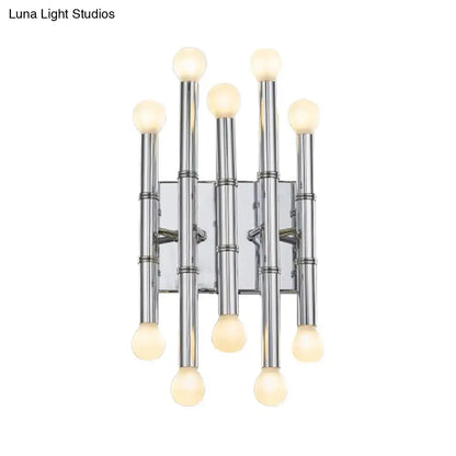 Modern polished gold wall sconce with five slender metal tubes shaped like bamboo holding frosted globe bulbs