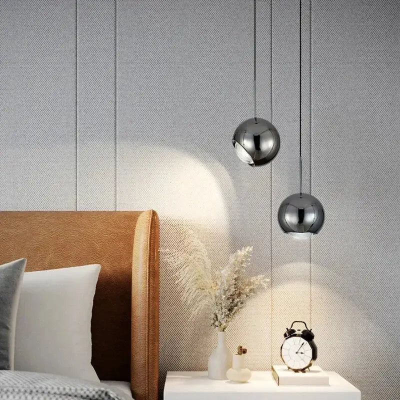 Two sleek chrome polished metallic pendant lights with adjustable angle hang above a white nightstand decorbites adjustable angle