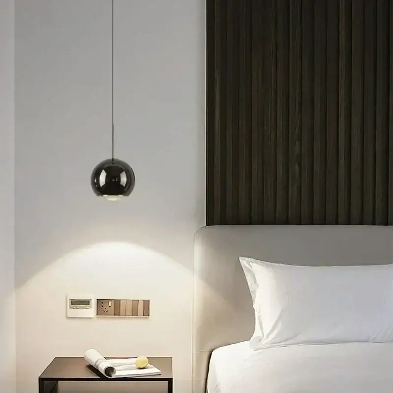 A sleek spherical black pendant light with polished metallic finish and adjustable angle for modern dining room decorbites