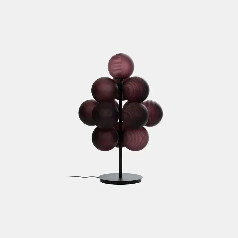 A modern floor lamp with deep burgundy decorbites glass bubble spheres on a slender black metal stem and base