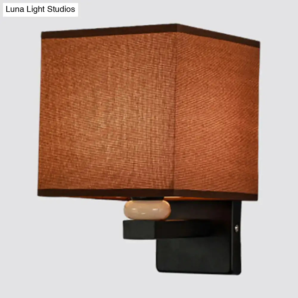 Modern rectangle wall light with brown fabric shade black metal base and off-white ceramic faux jade decor accent