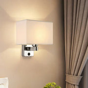 Modern rectangular chrome wall sconce with white beige fabric shade and metal base for bedroom lighting