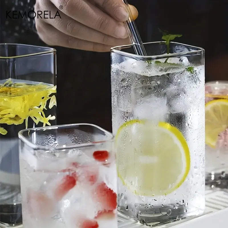 Modern rectangular clear glass highball glasses set with gold rim filled with ice and lemon slice for dining room use