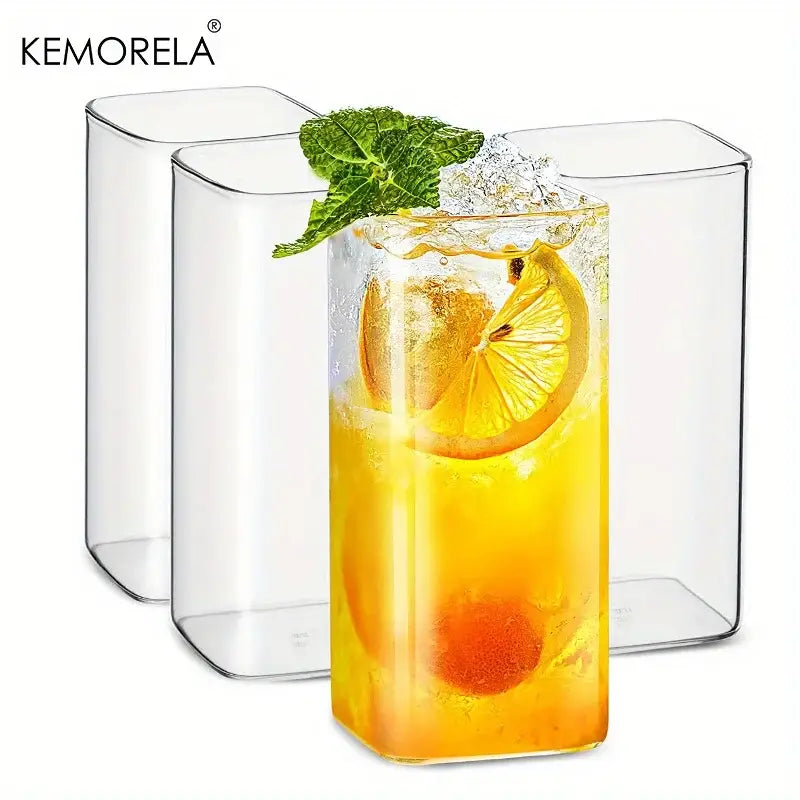 Modern rectangular clear glass highball glasses set featuring one glass filled with orange beverage and lemon garnish