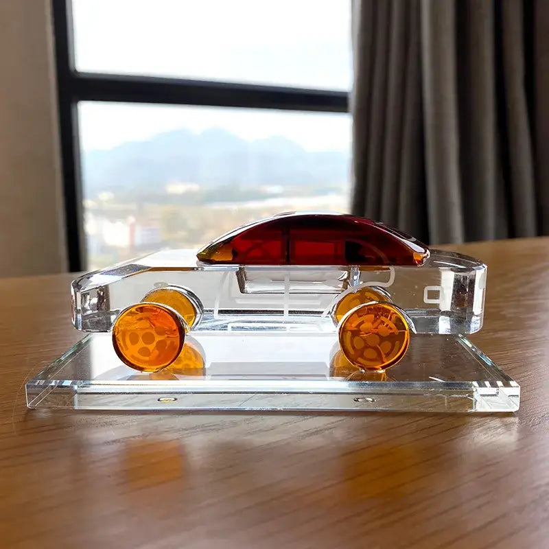 Modern red and blue crystal car model with amber wheels and red roof on a transparent base for office decor