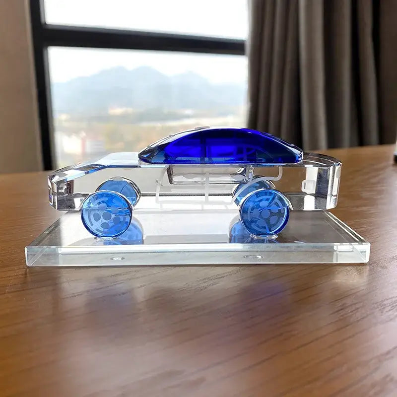 A sleek crystal car model with vibrant blue glass accents on roof and wheels for modern office table decor
