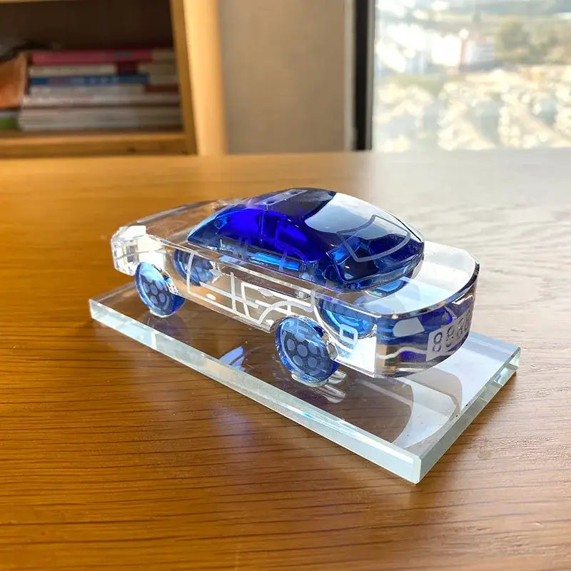 Translucent blue and clear glass crystal car model with intricate internal detailing on a matching transparent base for office decor