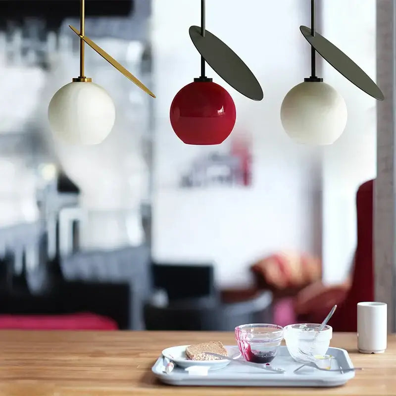 Three modern pendant lights with spherical glass shades in white and glossy red decorbites cherry led pendant above table