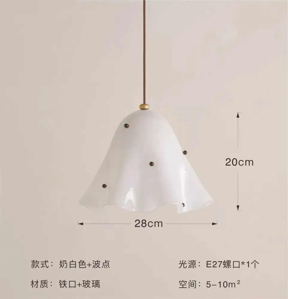 A delicate white glass pendant light with black dots and brass chain suitable for modern dining room lighting