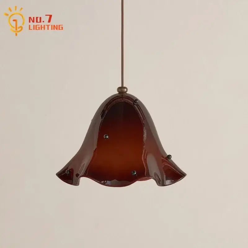 A glossy amber glass pendant light with bell-shaped fluted design and metallic accents for modern dining rooms