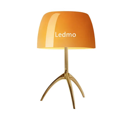 Modern table lamp with orange glossy glass shade and gold-toned tripod base for bedroom lighting
