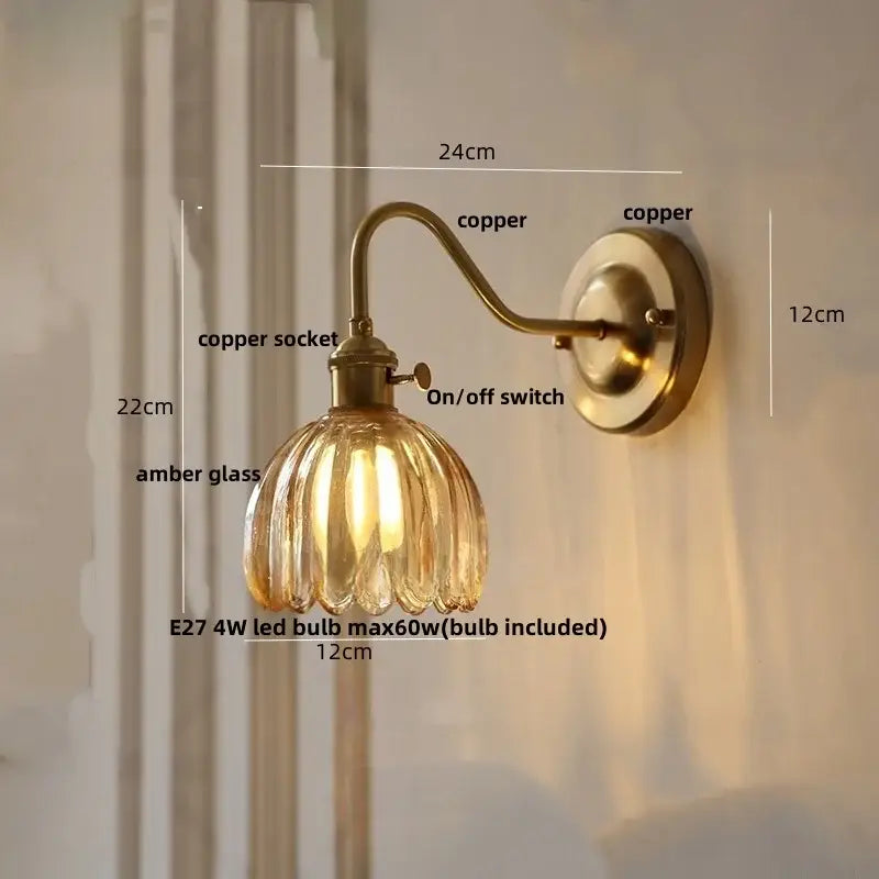 Antique brass-finished wall sconce with ribbed amber glass shade and glass copper knob switch for bedroom use