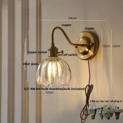 Modern wall sconce with antique brass finish and clear ribbed glass shade featuring a glass copper knob switch
